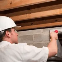 Termite inspection technician checking a basement wall and framing for termite activity in Cambridge, MA